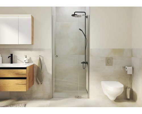 Moderne badkamer met glazen douche, houten wastafelmeubel, hangend toilet en donkere douchekraan in een licht betegelde ruimte.