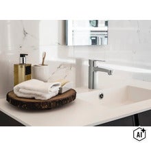 Moderne verchroomde wastafelkraan met eenhendelmengkraan op een wastafel voor een muur met marmerlook tegels in de badkamer. (Image AI modified or generated)