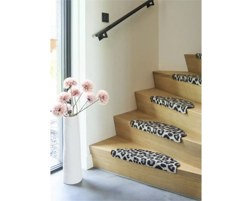 Houten trap met traptreden in luipaardprint, decoratieve vloervaas met kunstbloemen en zwarte trapleuning in de woonkamer.
