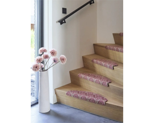 Trapmatten met ornamentaal patroon op een houten trap, gedecoreerd met een hoge vloervaas en kunstbloemen in een modern interieur.