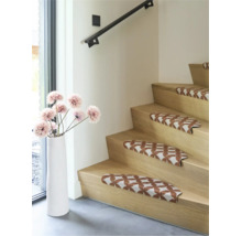 Houten trap met patroon trapmatten en een witte vloervaas met bloemen in een modern, licht interieur.