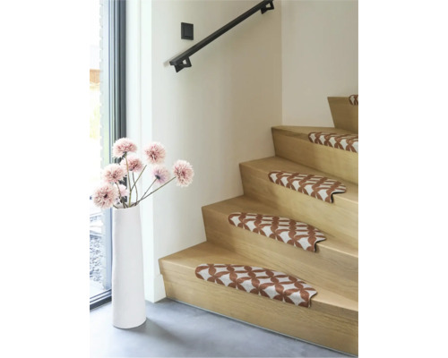 Houten trap met patroon trapmatten en een witte vloervaas met bloemen in een modern, licht interieur.
