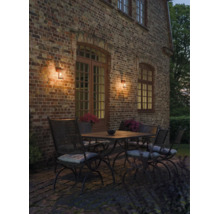 Sfeervolle buitenmuurlampen gemonteerd op een bakstenen gevel met terrasmeubilair in de schemering.