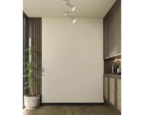 Moderne plafondspots aan een lichte muur in een stijlvol interieur met houtaccenten en een plant.