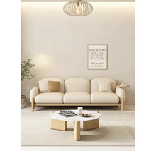 Lichte woonkamer met een driezitsbank, een ronde salontafel van hout en marmer, een vloerkleed, een moderne hanglamp en een wanddecoratie.
