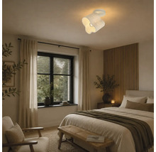 Moderne plafondlamp met golvend ontwerp gemonteerd in een gezellige slaapkamer met een wand van houten latten.
