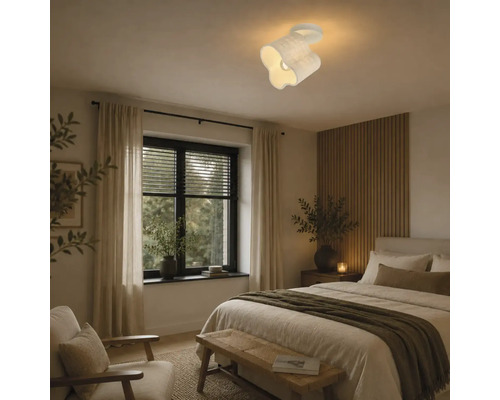 Moderne plafondlamp met golvend ontwerp gemonteerd in een gezellige slaapkamer met een wand van houten latten.