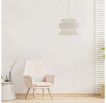 Moderne hanglamp met getextureerde kap boven een comfortabele fauteuil in een lichte, gezellig ingerichte kamer.