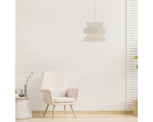 Moderne hanglamp met getextureerde kap boven een comfortabele fauteuil in een lichte, gezellig ingerichte kamer.