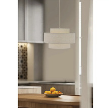 Moderne hanglamp met textielen kap in drie lagen boven een houten tafel met een fruitschaal in een stijlvol ingerichte keuken.