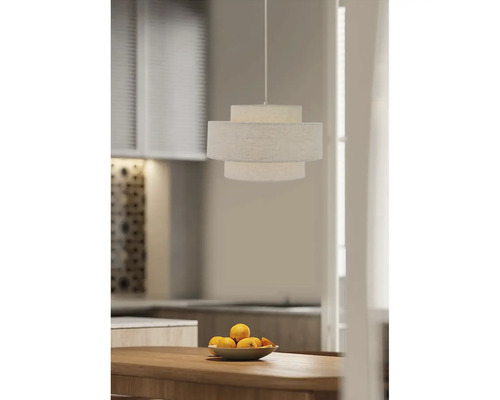 Moderne hanglamp met textielen kap in drie lagen boven een houten tafel met een fruitschaal in een stijlvol ingerichte keuken.