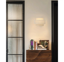 Moderne wandlamp van textiel in modern interieur met houten ladekast en boeken.