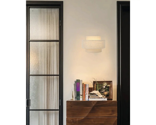 Moderne wandlamp van textiel in modern interieur met houten ladekast en boeken.