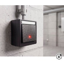 Vochtbestendige wipschakelaar met controlelampje voor opbouwmontage op een muur. (Image AI modified or generated)