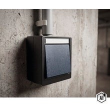 Opbouw lichtschakelaar in een robuuste behuizing gemonteerd op een betonnen muur met kabelgeleiding. (Image AI modified or generated)