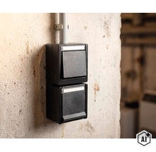Dubbele opbouwschakelaar in een robuuste behuizing voor installatie in vochtige ruimtes op een ruwe betonnen muur. (Image AI modified or generated)