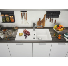 Moderne witte keukenspoelbak met afdruiprek en keukenkraan in een georganiseerde keuken met een donker aanrechtblad.