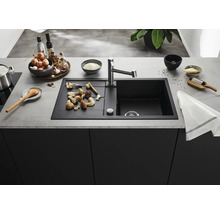 Moderne spoelbak met afdruiprek en keukenkraan in een georganiseerde keukenomgeving met keukengerei en ingrediënten op het aanrechtblad.