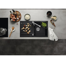 Moderne zwarte inbouwspoelbak met afdruipblad en keukenkraan in een georganiseerde keuken met keukengerei en verse ingrediënten.