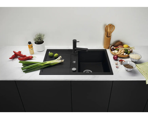 Moderne zwarte inbouwspoelbak met afdruiprek en bijpassende keukenkraan in een stijlvolle keuken met voedsel op het aanrecht