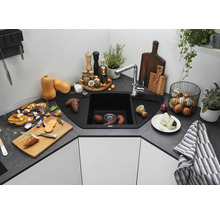Hoekspoelbak met kraan in een moderne keuken met werkblad in steenlook, omringd door keukengerei en etenswaren.