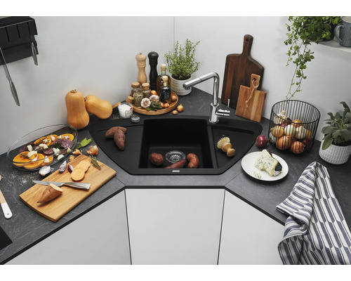 Hoekspoelbak met kraan in een moderne keuken met werkblad in steenlook, omringd door keukengerei en etenswaren.