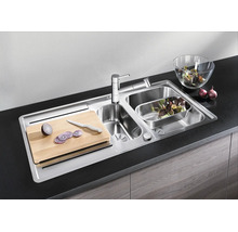 Roestvrijstalen inbouwspoelbak met twee spoelbakken, kraan, snijplank en accessoires in een moderne keuken.