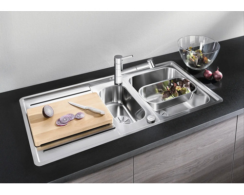 Roestvrijstalen inbouwspoelbak met twee spoelbakken, kraan, snijplank en accessoires in een moderne keuken.