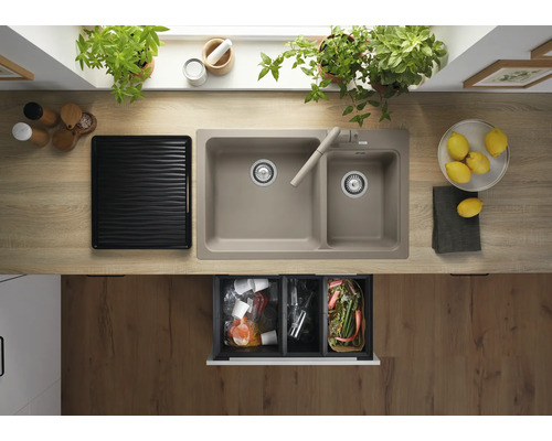 Keukenspoelbak met twee spoelbakken en kraan ingebouwd in een licht houtlook werkblad met een open afvalscheidingssysteem eronder