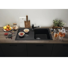 Moderne zwarte inbouwspoelbak met afdruiprek en bijpassende kraan in een keuken met houtlook werkblad en donkere keukenkastjes.