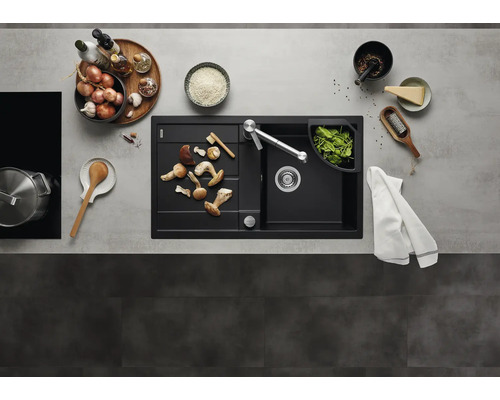 Moderne zwarte inbouwspoelbak met afdruipblad en keukenkraan in een georganiseerde keuken met keukengerei en verse ingrediënten.