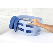 Ovale kunststof wasmand met handgrepen en ventilatieopeningen gevuld met een handdoek op een plank.