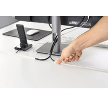 Persoon leidt kabels door een kabelgoot op een bureau voor kabelmanagement.