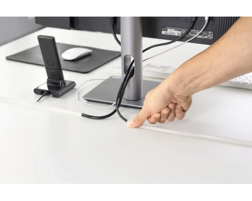 Persoon leidt kabels door een kabelgoot op een bureau voor kabelmanagement.