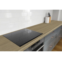 Moderne keukenopstelling met houtstructuur werkblad, inductiekookplaat, oven en witte wandtegels.