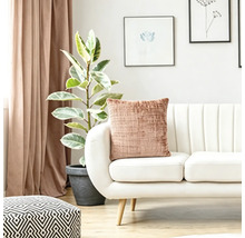 Structuurkussen op een moderne witte bank in een lichte woonkamer met kamerplant en gordijnen