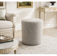 Ronde gestoffeerde poef met gestructureerde bekleding in een elegante woonkamer met antieke meubels.