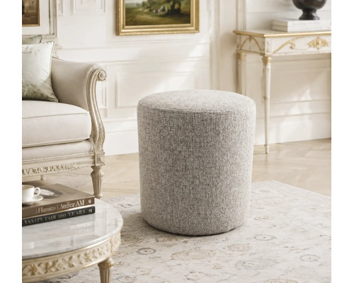 Ronde gestoffeerde poef met gestructureerde bekleding in een elegante woonkamer met antieke meubels.