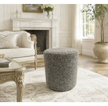 Ronde gestoffeerde poef met textuur in een elegante woonkamer met open haard.
