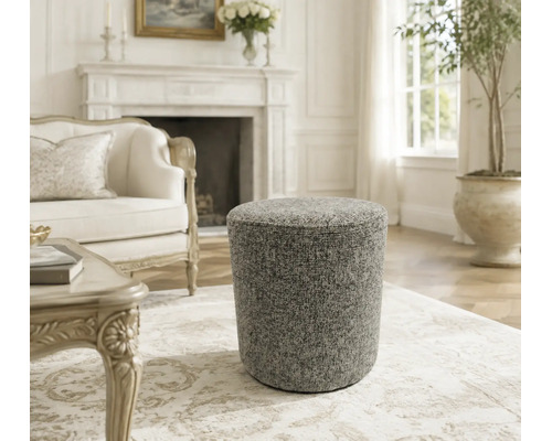 Ronde gestoffeerde poef met textuur in een elegante woonkamer met open haard.