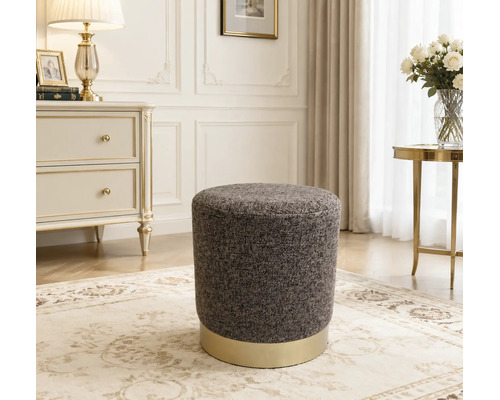 Ronde gestoffeerde poef met textuur en een metalen voet in een klassiek ingerichte woonkamer.