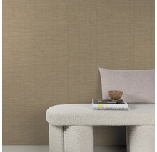 Gestructureerd vliesbehang in beige met een fijn lijnenpatroon gecombineerd met een bankje en sierkussens voor een muur.