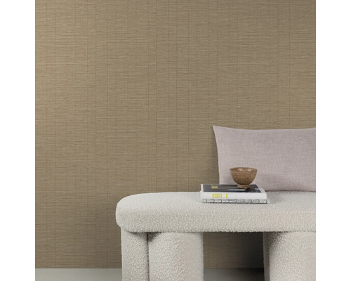 Gestructureerd vliesbehang in beige met een fijn lijnenpatroon gecombineerd met een bankje en sierkussens voor een muur.