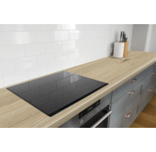 Moderne keuken met houtlook werkblad, ingebouwde kookplaat, oven en een witte tegelwand in landelijke stijl.