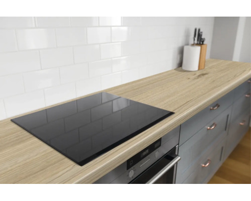 Moderne keuken met houtlook werkblad, ingebouwde kookplaat, oven en een witte tegelwand in landelijke stijl.