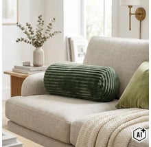 Cilindervormig sierkussen met geribbelde structuur op een moderne bank in een lichte woonkamer. (Image AI modified or generated)