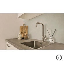 Moderne roestvrijstalen gootsteen met eenhendelmengkraan op een werkblad in betonlook met decoratieve objecten. (Image AI modified or generated)