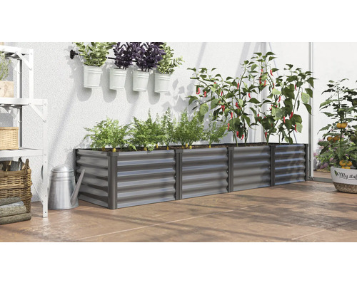 Rechthoekige metalen plantenbak in een kas met diverse planten zoals paprika en wortels op een terrasvloer.