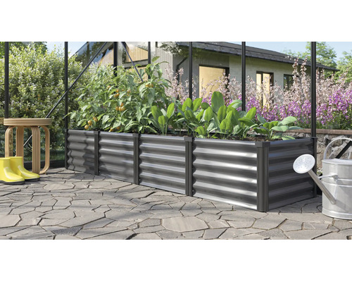 Rechthoekige metalen verhoogde plantenbak in een kas, beplant met tomaten en sla op een bestraat terras in de tuin.