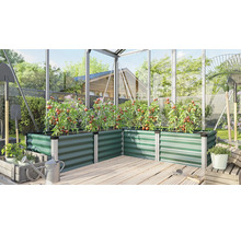 Groene verhoogde plantenbak van metaal in een kas met tomatenplanten op een houten terras.